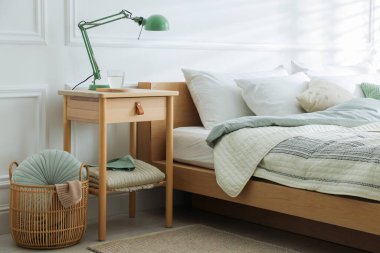 Yatak odasının yanında lamba ve bir bardak su olan komodinin yanında.