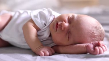 Sevimli yeni doğmuş bebek yatağın içinde uyuyor, yakın plan.