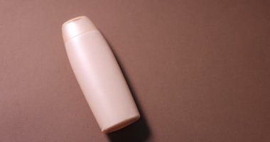 Kahverengi arka planda kozmetik ürünler ve çiçekler düzenleyen kadın, yakın plan