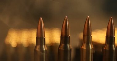 Koyu arkaplanda ateşli silah fişekleri, dumanlı, yakın plan. Kamera sağa hareket ediyor