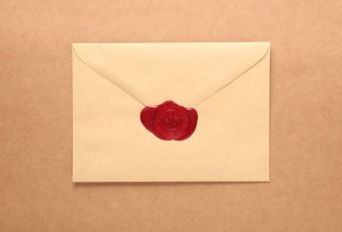 Bej arka planda kırmızı balmumu mühürü olan güzel bir zarf, üst manzara