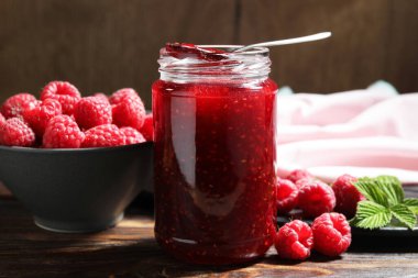 Cam kavanozda nefis ahududu reçeli, kaşık, taze böğürtlen ve nane.