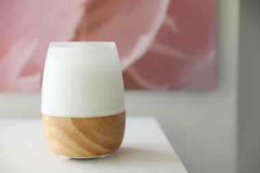 Beyaz ahşap masada modern aroma lambası, yakın plan. Metin için boşluk