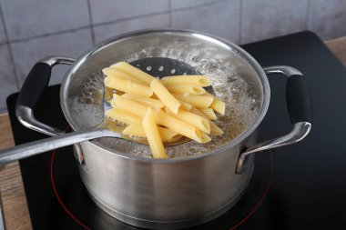 Elektrikli ocakta kaynar suyla haşlanmış makarnadan makarna alıp yakın plan çekiyoruz.