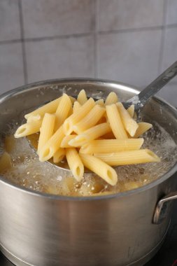 Elektrikli ocakta kaynar suyla haşlanmış makarnadan makarna alıp yakın plan çekiyoruz.