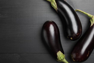 Siyah ahşap masada taze patlıcanlar, düz yatış. Metin için boşluk