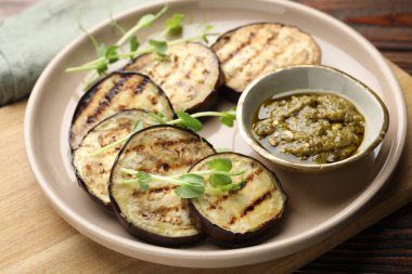 Ahşap masada soslu ızgara patlıcan dilimleri ve mikroyeşiller, yakın plan.