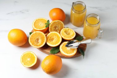 Taze sıkılmış portakal suyu, meyve suyu ve meyve sıkacağı beyaz masada.