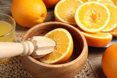 Sıkılmış portakallar meyve sıkacağı ve bir bardak meyve suyu, ahşap masa, yakın plan.