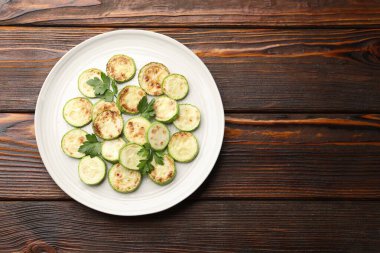 Ahşap masada maydanozlu lezzetli kızarmış kabak dilimleri, üst manzara. Metin için boşluk