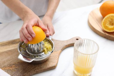 Meyve suyu. İçerideki beyaz mermer masada portakal suyu kullanan kadın, yakın plan.