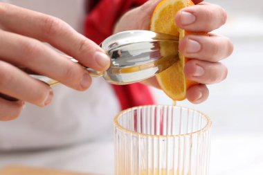 Meyve suyu. Kapalı alanda meyve sıkacağı kullanan portakallı kadın, yakın plan.