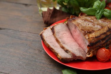 Lezzetli pişmiş et, domates ve fesleğen, ahşap masada, yakın plan. Metin için boşluk