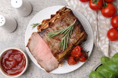 Lezzetli pişmiş et, domates, fesleğen, biberiye ve sos gri masada, düz yatıyordu.