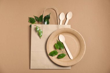 Farklı çevre dostu ambalaj, sofra takımı ve açık kahverengi arka planda yapraklar, düz uzanma