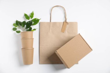 Farklı çevre dostu ambalaj, beyaz arka planda fincanlar ve yapraklar, düz uzanma