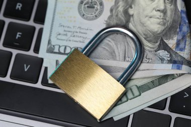 Siber güvenlik. Metal asma kilit ve dolar dizüstü bilgisayarda, üst görünümde.