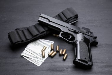 Silah, fişekler ve siyah arkaplanda dolar banknotları