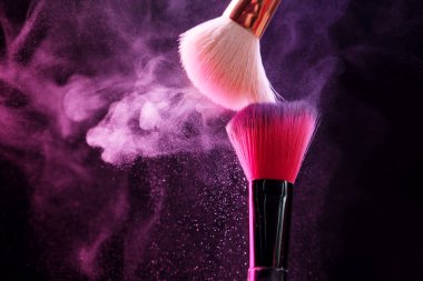 Renkli göz gölgeli makyaj fırçaları siyah arka planda neon ışıkları, yakın plan. Metin için boşluk