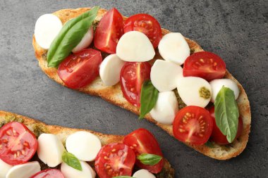 Mozarella peynirli, domatesli ve fesleğenli lezzetli sandviçler gri desenli masa, düz uzanış