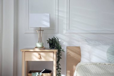 Yatağın içinde lamba ve diğer dekorlarla birlikte komodinin yanında.