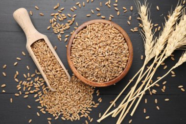 Kâsede buğday taneleri, siyah ahşap masada kepçeler ve çiviler, düz uzanmış.