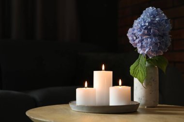 Evdeki ahşap masada yanan mumlar ve ortanca çiçekleri. Metin için boşluk