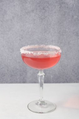 Martini kokteyli, bardakta şeker, gri duvarın yanındaki beyaz masada.