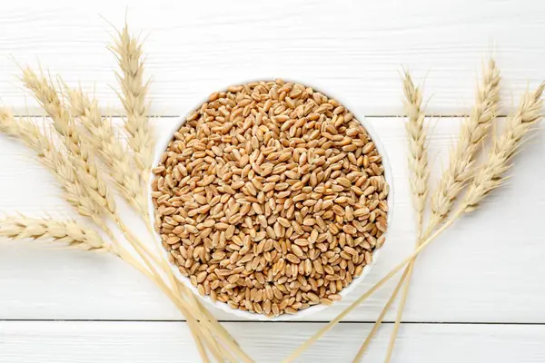 Kasede buğday taneleri, beyaz tahta masada çiviler, düz uzanmış.