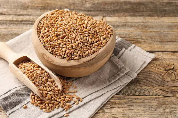 Kase içinde buğday taneleri ve ahşap masaya kepçe, yakın çekim. Metin için boşluk