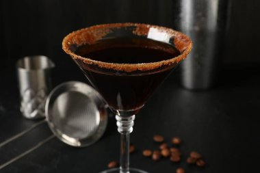 Bardakta şekerli martini kokteyli ve siyah masada kahve çekirdekleri, yakın plan.