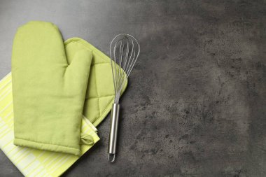 Yeşil fırın eldiveni, tutacağı, havlu ve çırpılmış koyu desenli masa, düz yatak. Metin için boşluk