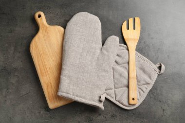 Gri fırın eldiveni ve diğer mutfak gereçleri koyu dokulu masa üzerinde, düz yatıyordu.