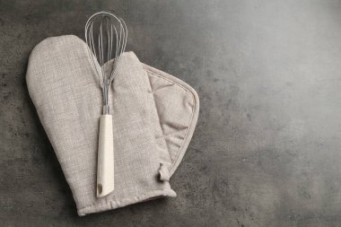 Gri fırın eldiveni, tutkal ve koyu dokulu masa çırpısı, üst manzara. Metin için boşluk