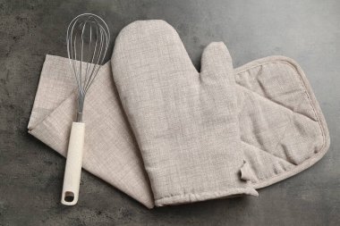 Gri fırın eldiveni, tutkal, havlu ve çırpılmış koyu desenli masa, düz uzanma