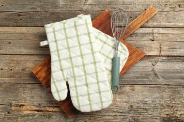 Fırın eldiveni ve diğer mutfak gereçleri ahşap masada, üst tarafta.