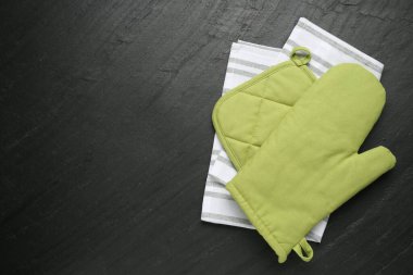Yeşil fırın eldiveni, havlu ve tutacağı koyu dokulu masa, üst manzara. Metin için boşluk
