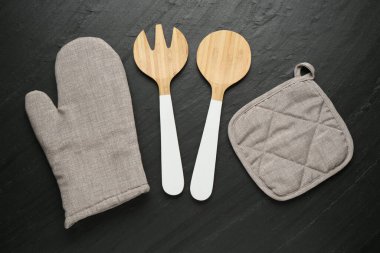 Gri fırın eldiveni ve diğer mutfak gereçleri koyu dokulu masa üzerinde, düz yatıyordu.