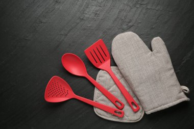 Gri fırın eldiveni ve diğer mutfak gereçleri koyu dokulu masa üzerinde, düz yatıyordu.