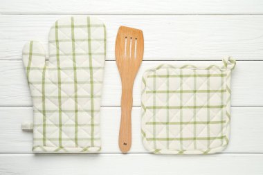 Fırın eldiveni, tutucu ve beyaz ahşap masa üzerinde spatula, düz yatıyordu.