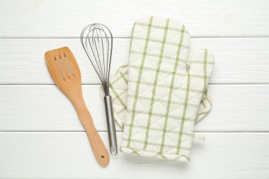 Fırın eldiveni, tutucu, çırpıcı ve spatula beyaz ahşap masa, düz yatıyordu.