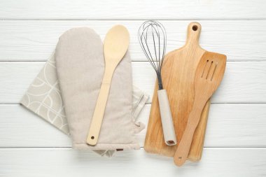 Fırın eldiveni ve diğer mutfak gereçleri beyaz ahşap masada, düz yatıyordu.