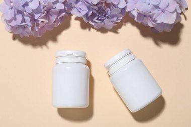 Kavanozlar dolusu vitamin ve çiçekler bej arka planda, düz yerde