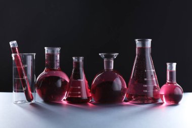 Siyah zemin üzerinde kırmızı sıvı bulunan laboratuvar camları