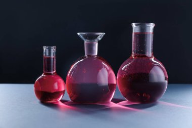 Siyah zemin üzerinde kırmızı sıvı bulunan laboratuvar camları