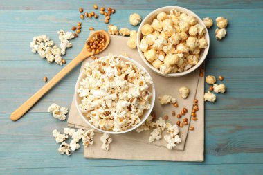 Lezzetli patlamış mısır ve mısır taneleri açık mavi ahşap masa, düz uzanmış