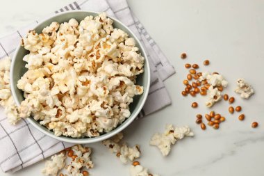 Lezzetli patlamış mısır ve mısır taneleri beyaz mermer masada, düz yerde.