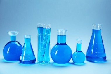 Açık mavi gradyan üzerinde parlak sıvı bulunan farklı bir laboratuvar camı.