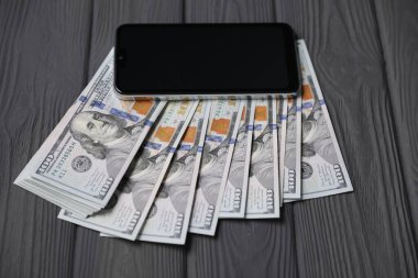 Akıllı telefon ve para gri ahşap masada, yakın plan.