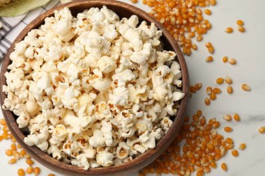 Lezzetli patlamış mısır ve mısır taneleri beyaz masada, düz yerde.